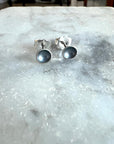 Pair of silver earrings with black centers on a marble surface